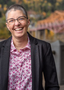 a very short-haired person wearing glasses is laughing during a professional photo shoot